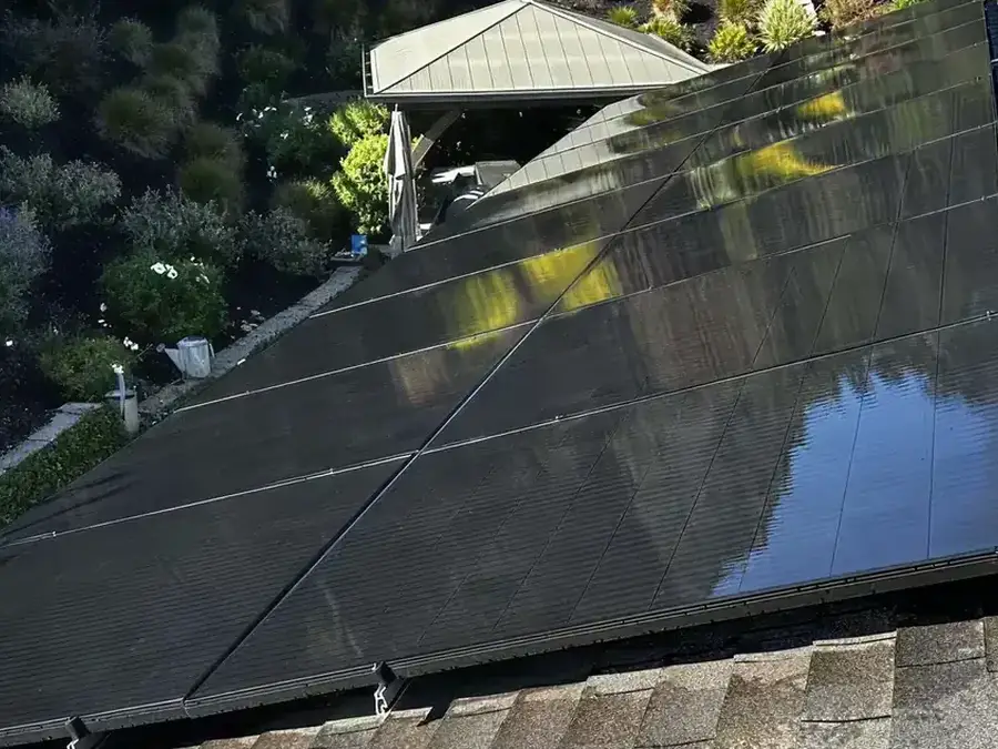 A residential rooftop solar array after cleaning, the glass mirroring the open sky