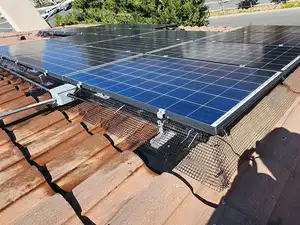 Black critter guard mesh installed along the tile roofline under the edge of a solar array.